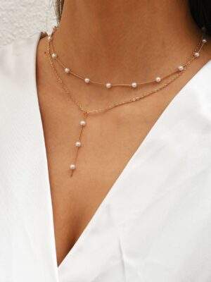 Collier à trois rangs avec perles blanches et chaînes dorées élégantes, parfait pour un style chic et féminin.